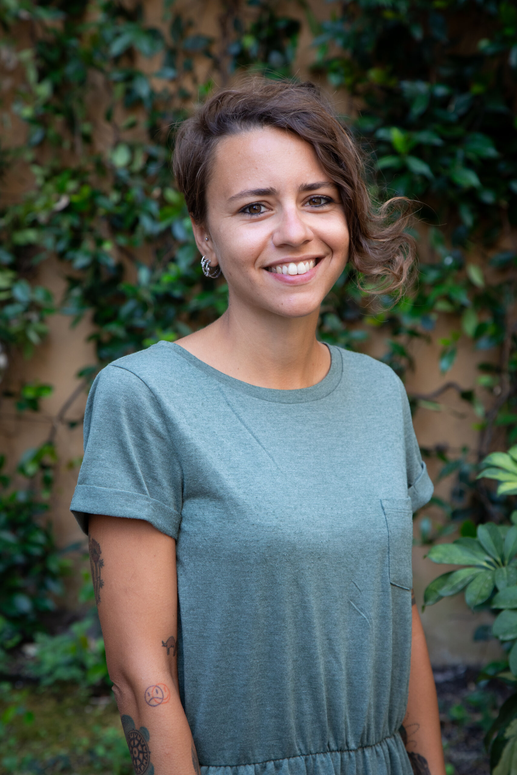 La foto rappresenta Giorgia Zignego, educatrice e pedagogista della cooperativa. Giorgia indossa una tuta unita di colore azzurro. Lo sfondo rappresenta il cortile d'entrata dell'edificio dove la cooperativa ha la sede in Via Agostino Oldoini 50 alla Spezia.